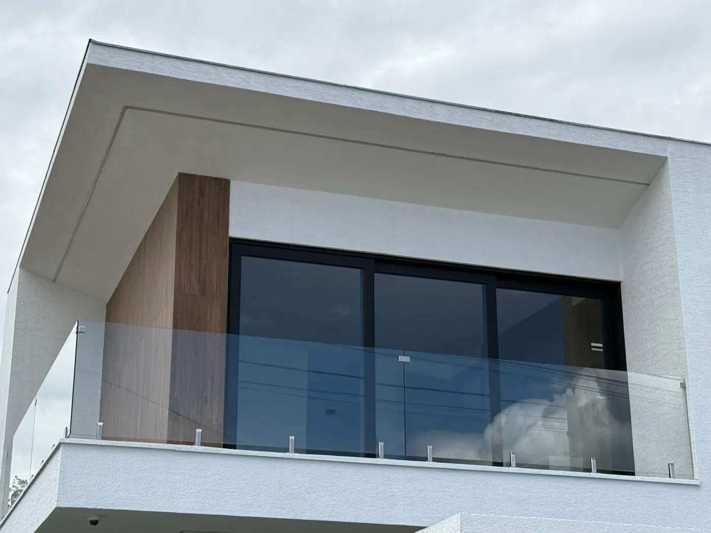 Balcón con barandilla de vidrio templado y ventana corrediza de aluminio